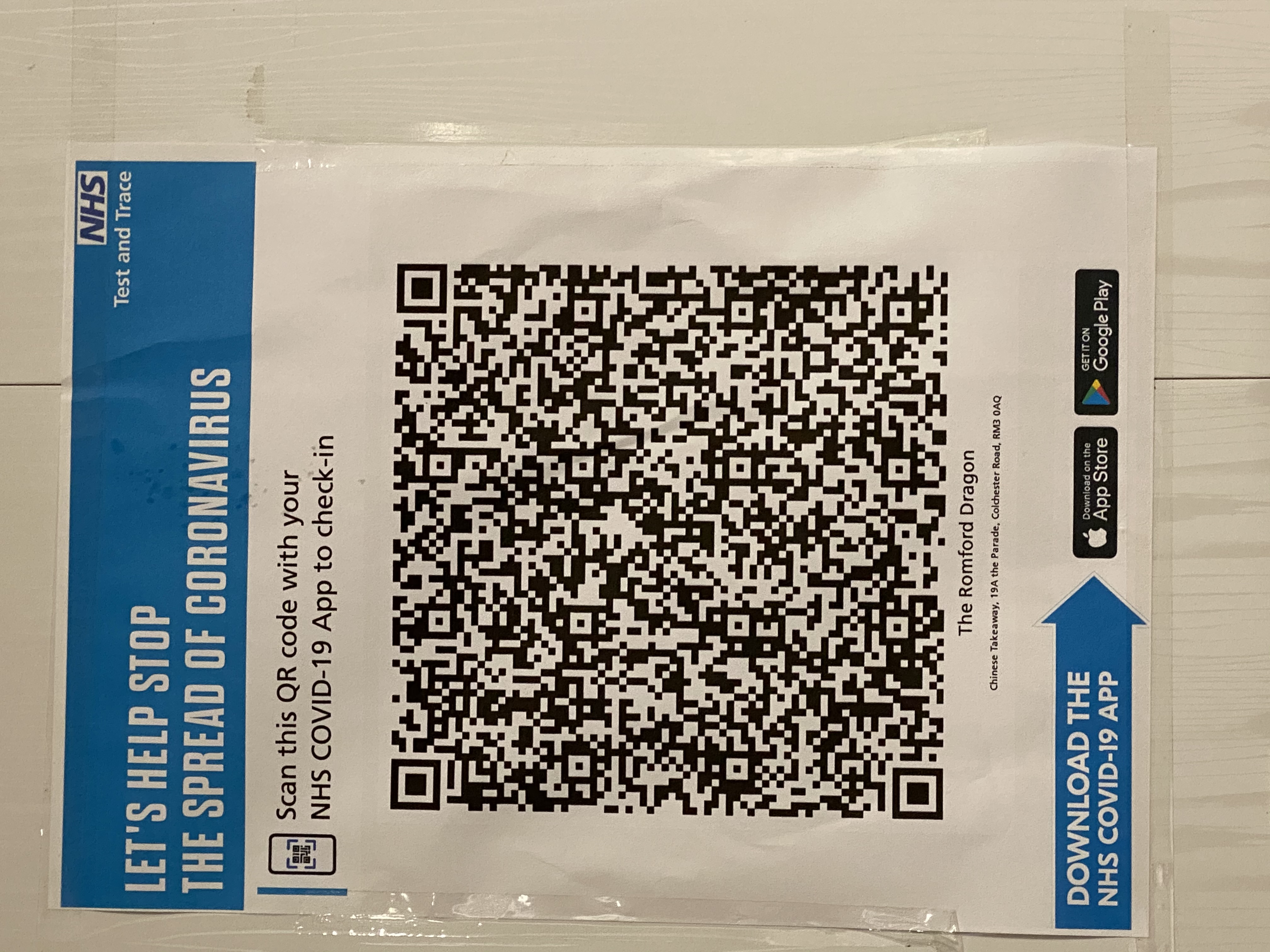 The printout of the NHS sign on a wall. It shows a QR code along with the text: 